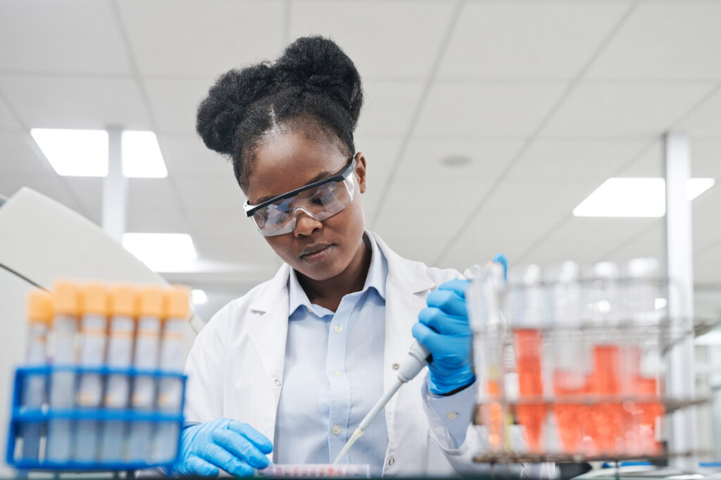 A woman wearing a white coat uses laboratory tools